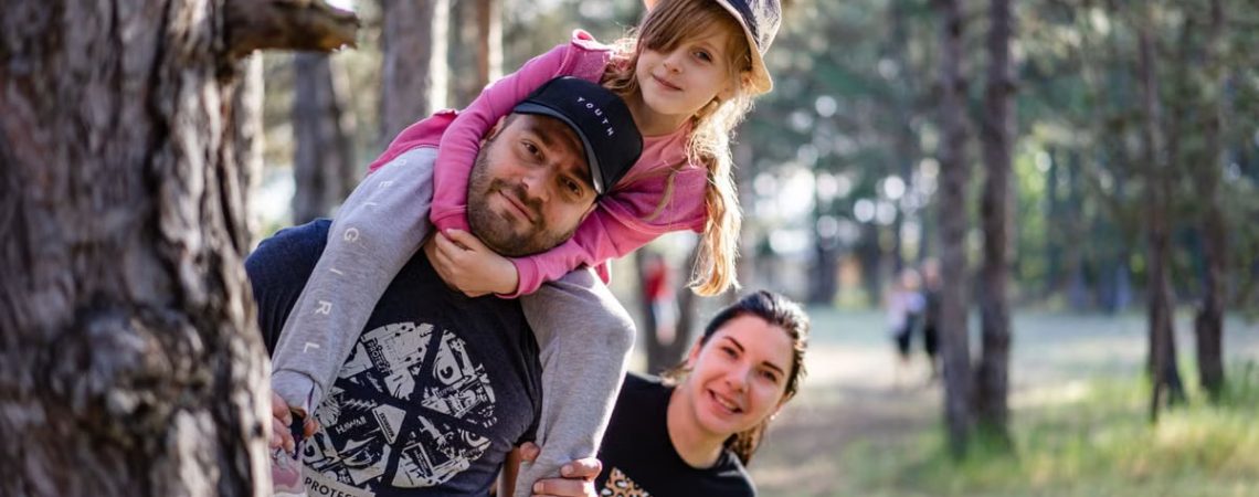 A joyful family enjoying a playful day in a sunlit forest park, capturing the essence of togetherness.
