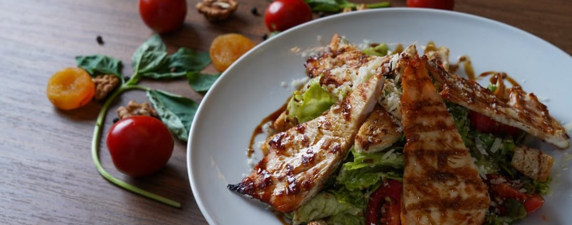 Delicious grilled chicken salad served with fresh tomatoes and walnuts on the side.